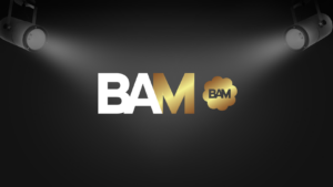 Logo for BAM with bold white and gold letters on a dark stage backdrop and spotlights shining down