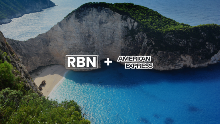 Coastal cove with turquoise water, sandy beach, and limestone cliffs, green vegetation on top; centered RBN logo with a plus sign and American Express logo to the right.
