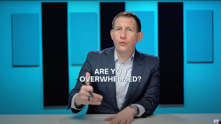Video thumbnail: man in a blazer speaking at a desk in a blue recording studio, with the text 'Are you overwhelmed?' overlaid