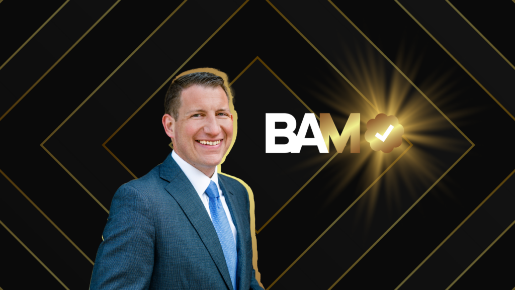 Smiling man in a blue suit stands beside the bold white letters 'BAM' with a gold checkmark badge and radiant glow on a black geometric background.