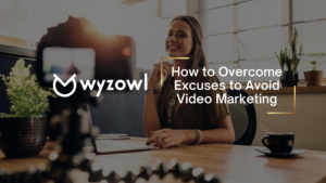 Hero image of a smiling woman at a desk with a camera in the foreground, overlay text reads 'How to Overcome Excuses to Avoid Video Marketing' with a Myzowl logo in the background.