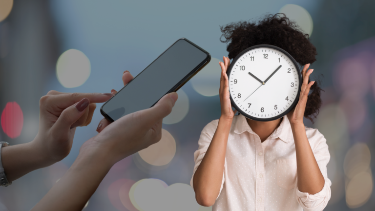 Person holds a large clock in front of their face while another person points a smartphone toward them, city lights blur in the background, suggesting time pressure or distraction.