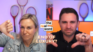 Split-screen of two hosts: woman on left gives thumbs-down, man on right gives thumbs-up; center logo reads 'the real word'; caption 'END OF LUXURY?' in orange letters.