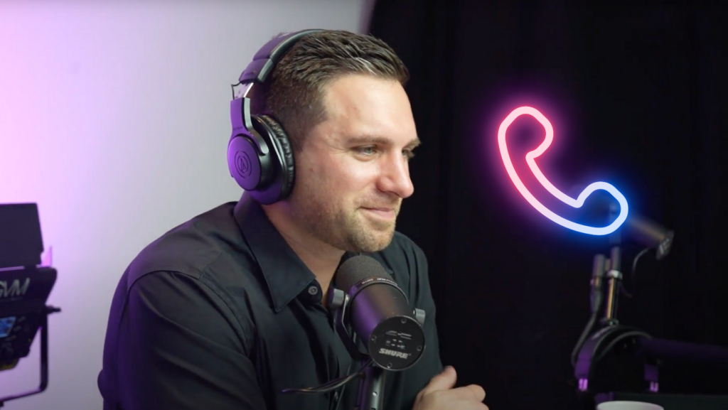 Podcast host wearing over-ear headphones speaks into a microphone in a studio with a neon phone icon in the background (right).