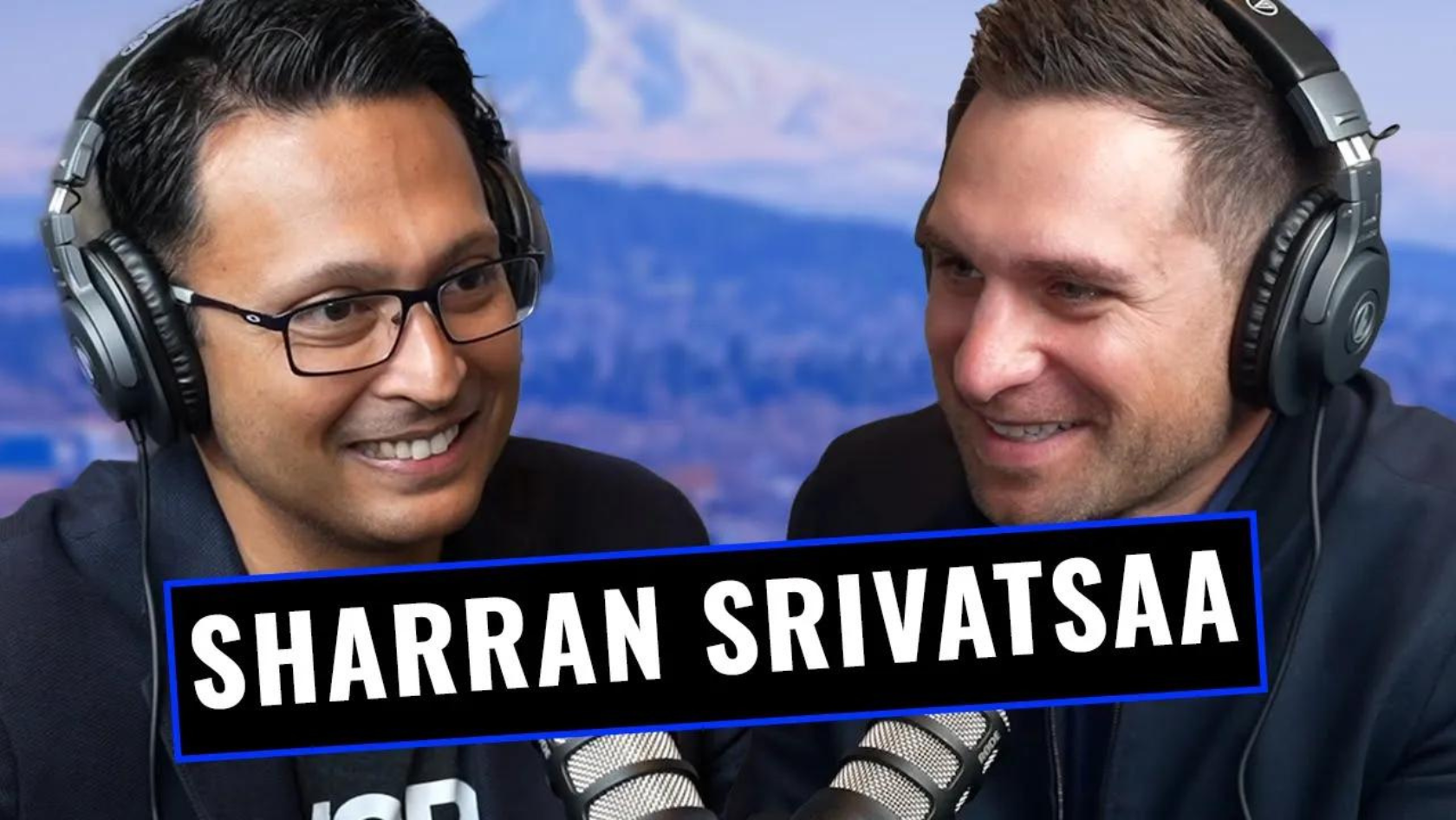 Two men wearing large over-ear headphones chat and smile during a podcast recording with microphones in front of them, a bold banner shows 'SHARRAN SRIVATSA' across the image.