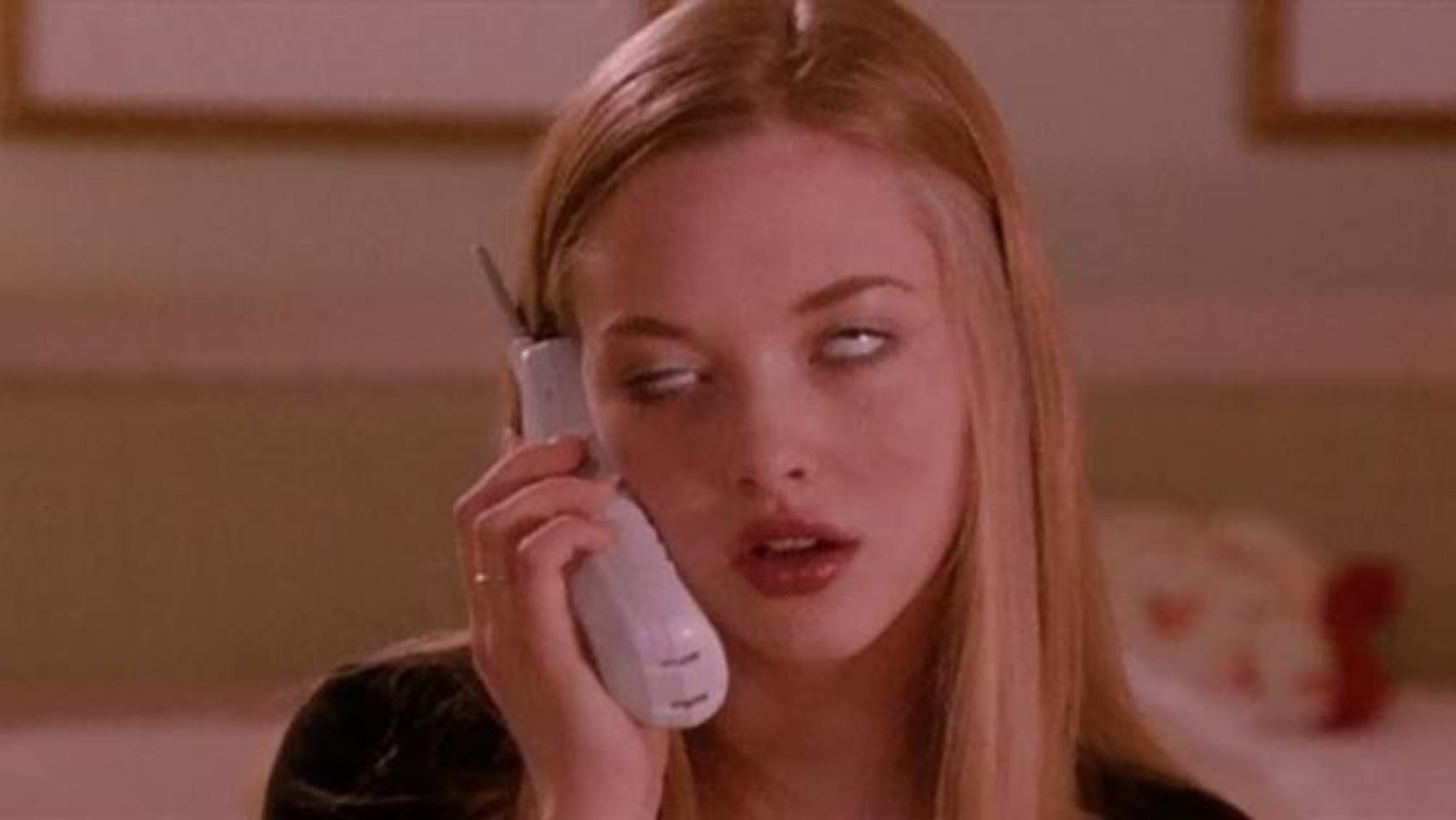 Woman with long blond hair on a landline phone, rolling her eyes as she speaks.