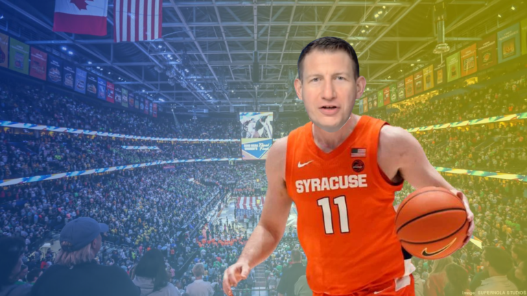 Male basketball player in an orange Syracuse jersey #11 dribbles toward the camera in a full arena.