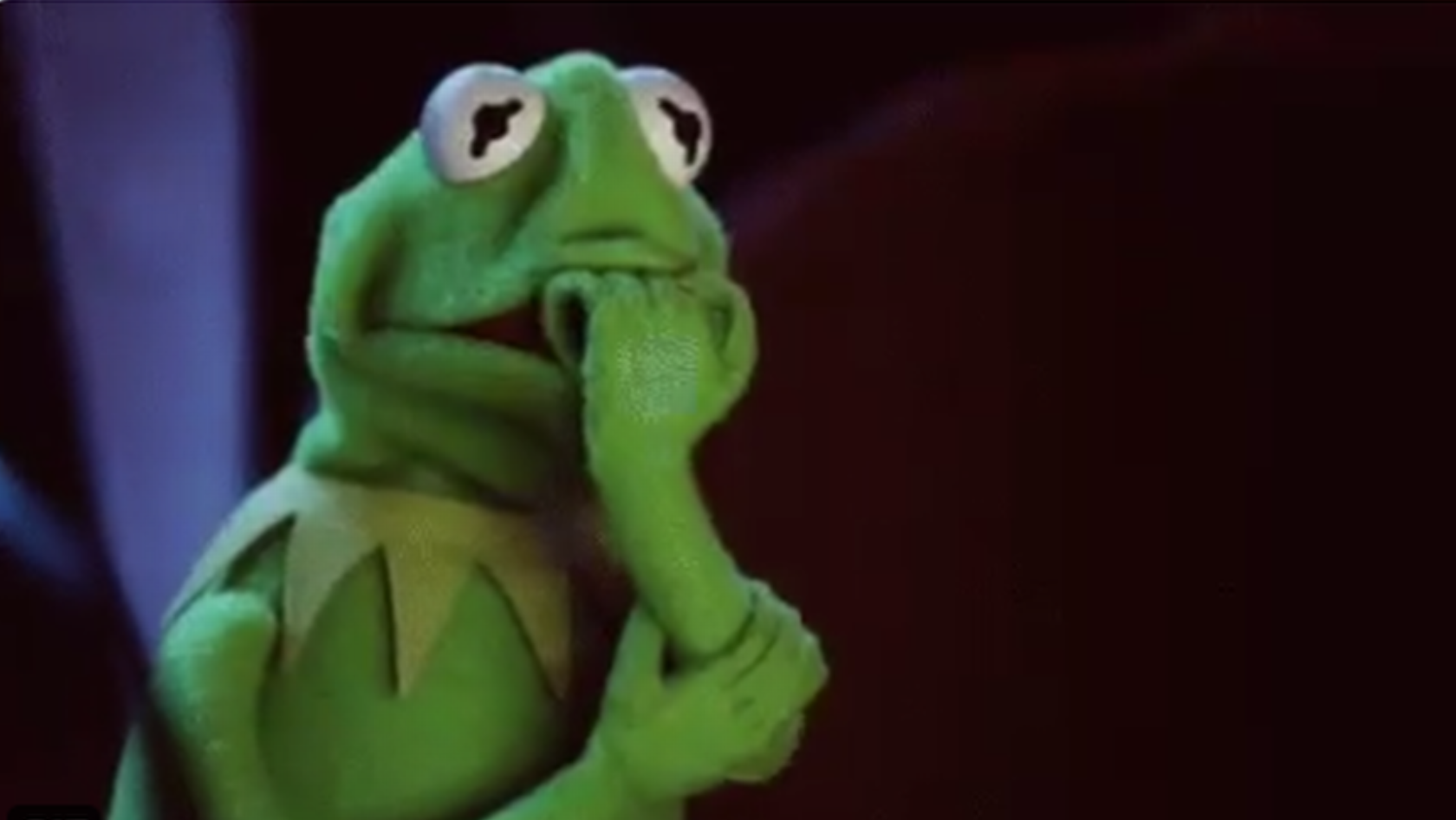 Kermit the Frog puppet with a thoughtful pose, hand resting on chin.
