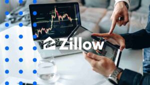 Zillow logo over a desk with a laptop showing stock charts and a person’s hands using a tablet, blue decorative dots overlaying the image.