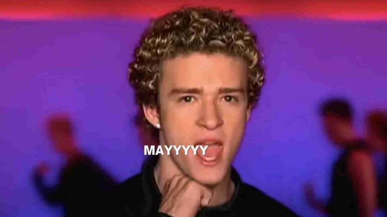 Close-up of a young man with curly hair, hand under chin, purple background, meme-style text 'MAYYYY' across the face.