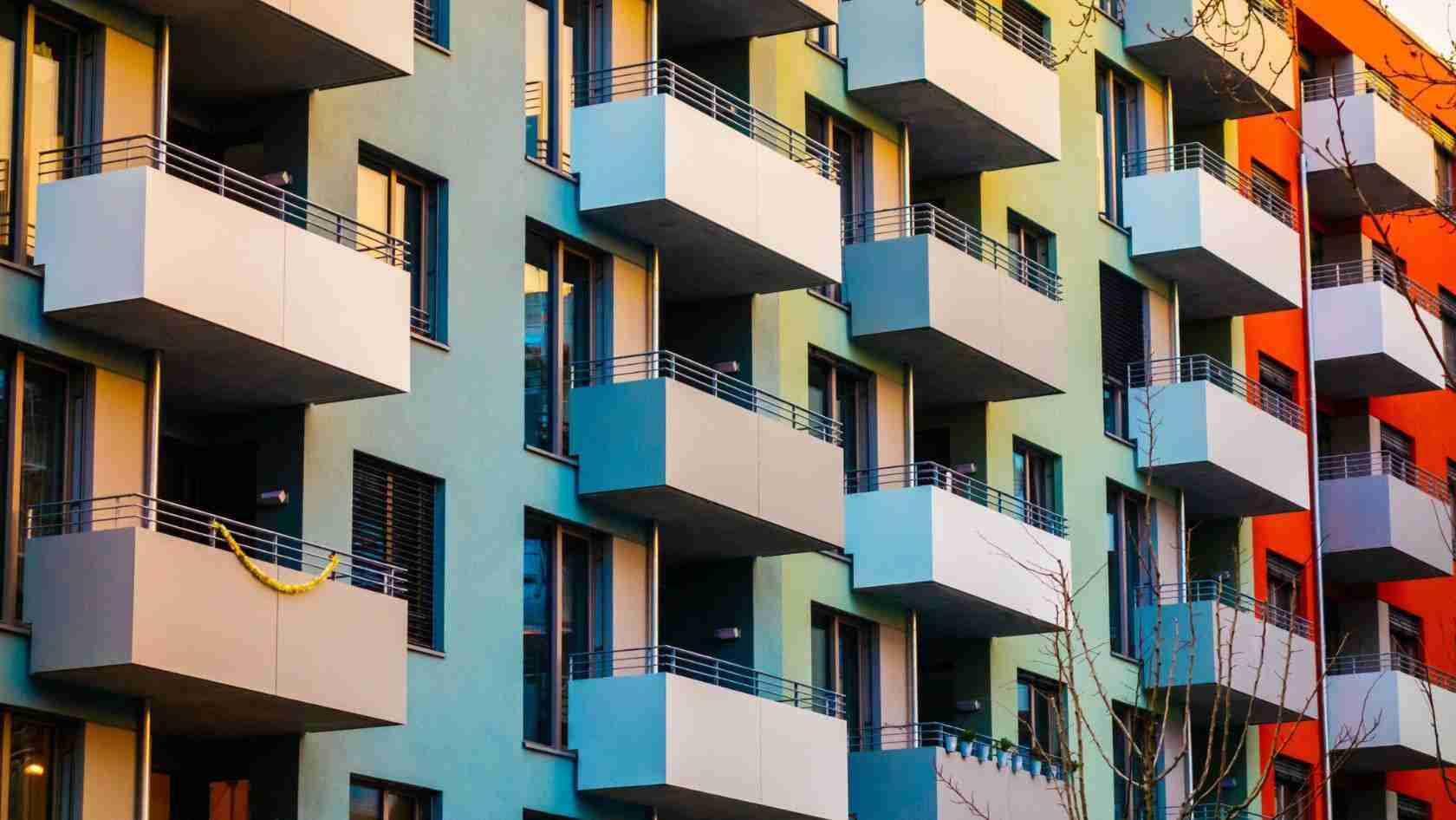 Multicolored apartment building with stacked balconies and large windows.
