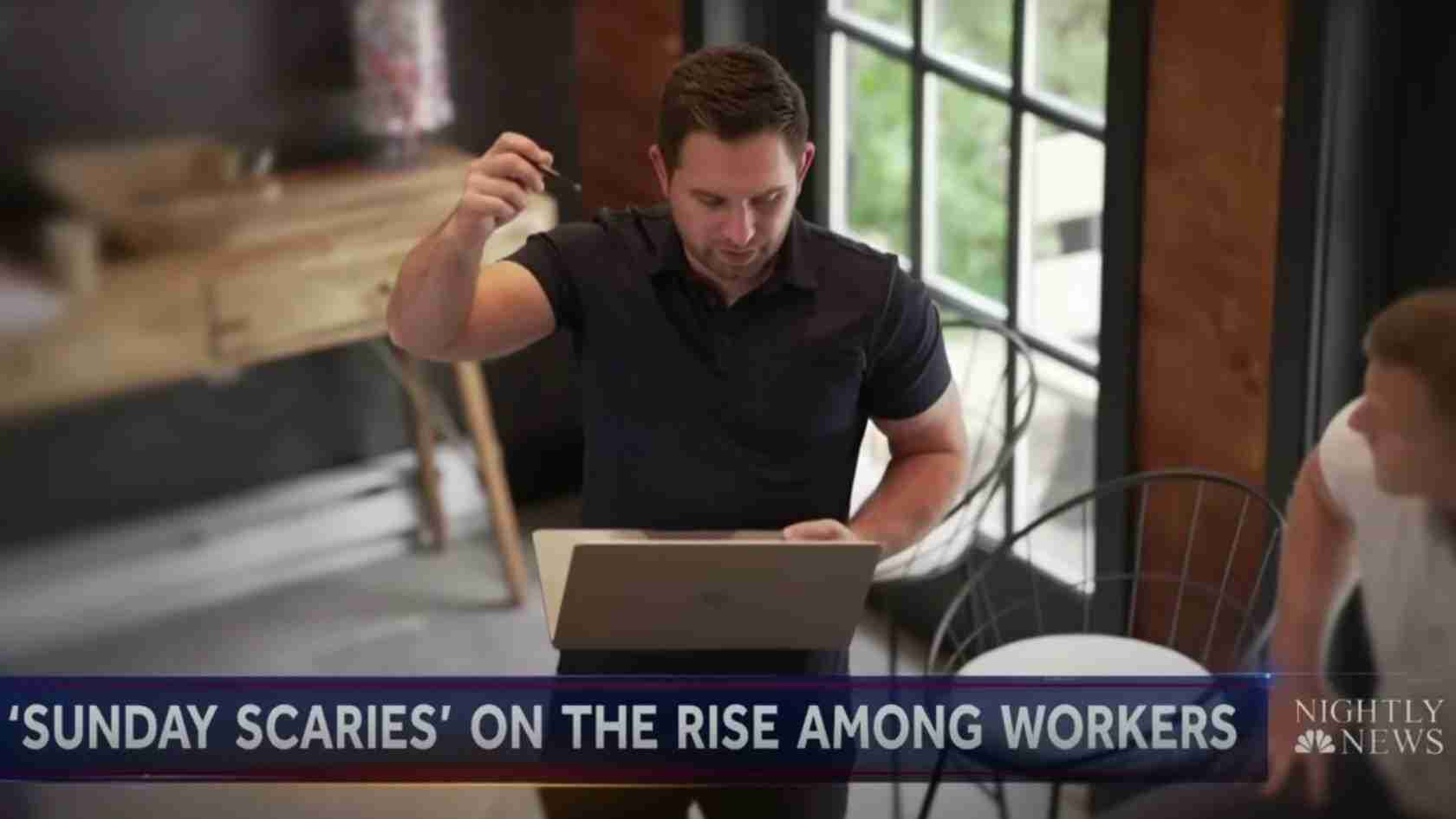 News screenshot: a man in a black polo uses a laptop at a desk in a modern office; caption reads 'Sunday Scaries' on the rise among workers, with Nightly News logo in the corner.