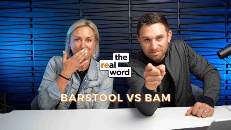 Two podcast hosts sit at a desk in a blue studio; the woman covers her mouth playfully, the man points at the camera, with the 'the real word' logo between them and 'BARSTOOL VS BAM' text below.