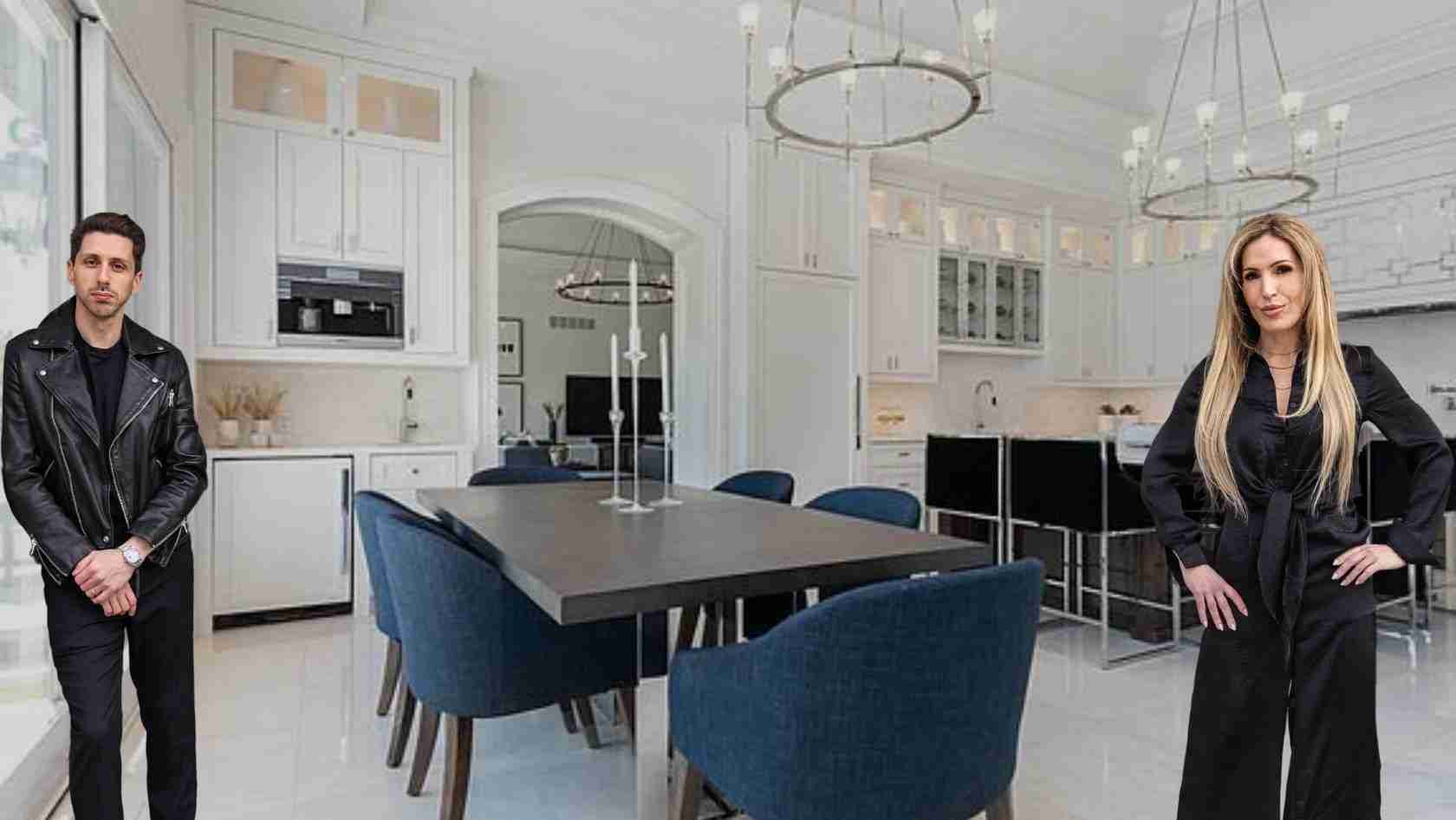 Two adults stand in a bright white kitchen around a dark dining table with blue chairs on either side of the room.