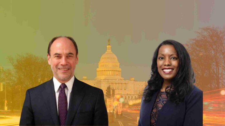 Two professionals in business attire pose in front of the U.S. Capitol with a city street behind them.