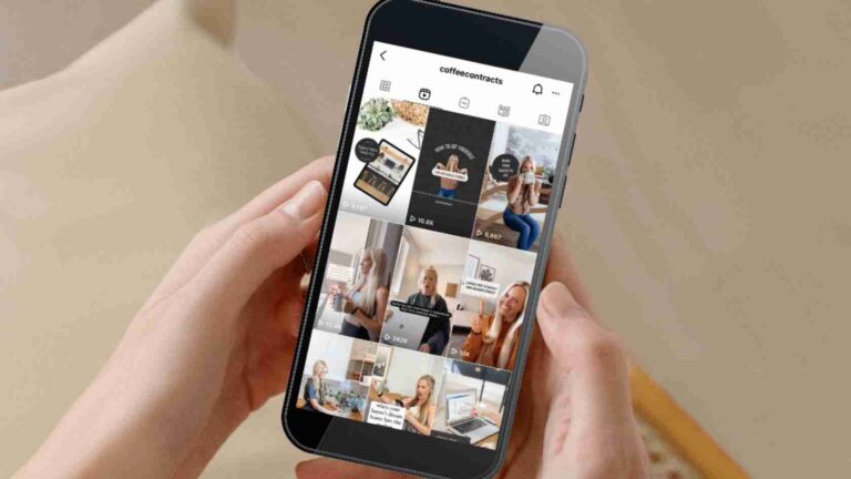 Person's hands hold a smartphone showing a grid view of video posts (reels) on a social media app against a beige background.