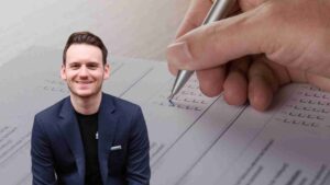 Smiling man in a navy blazer sits beside a close-up of a hand with a pen filling out a form with checkboxes.