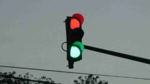 Traffic light with red and green signals visible on a pole against a gray sky.