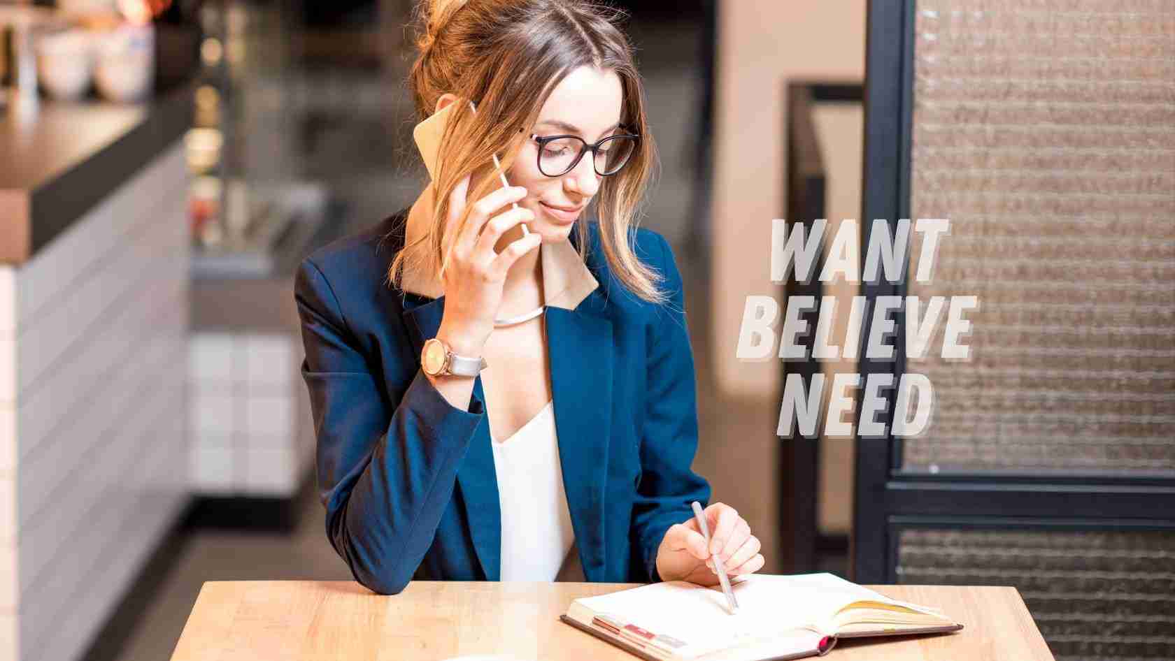 A woman in a blue blazer sits at a table in a cafe, talking on a mobile phone while writing in a notebook. Text on the image reads 'WANT BELIEVE NEED'.