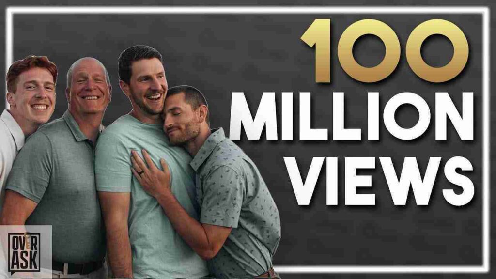Four men hugging and smiling in front of a dark banner that reads '100 MILLION VIEWS' with a gold '100' and an OverAsk logo in the corner.