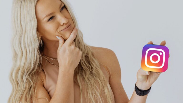 Woman with long blonde hair looking thoughtfully at a square card showing the Instagram logo held in her hand.