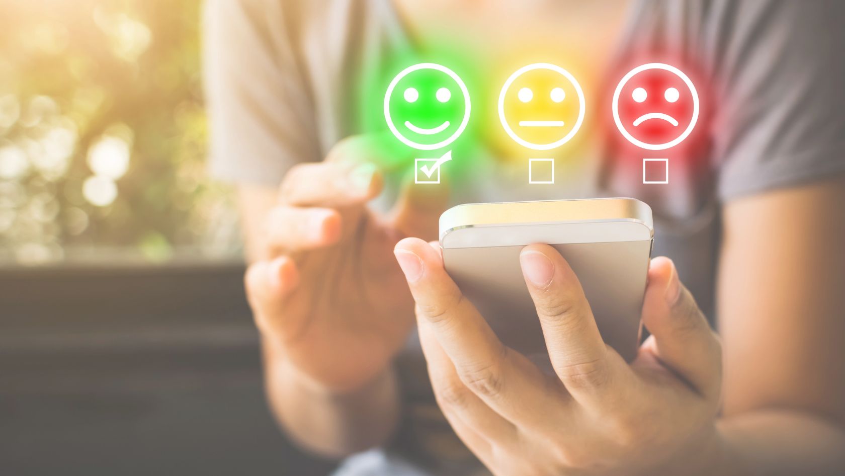 Person holding a smartphone with three mood icons above him: green happy, yellow neutral, red sad, symbolizing feedback options