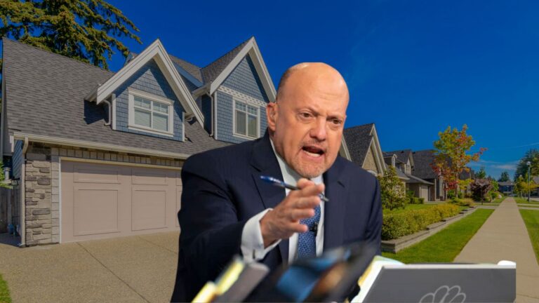 Man in a suit gesturing while speaking, with a large suburban house in the background.