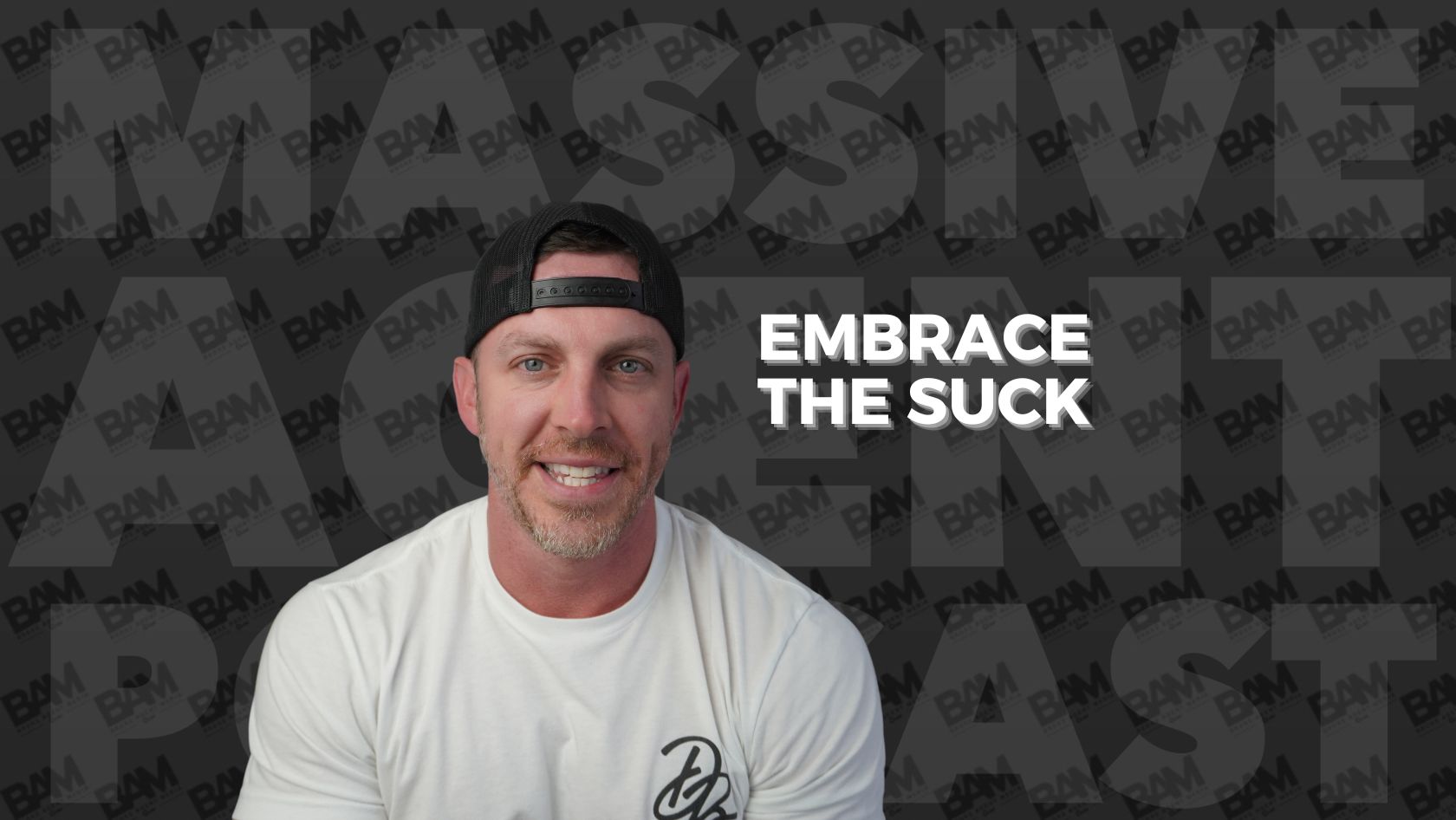 Smiling man in a white T‑shirt and backward black cap, with bold 'Embrace the Suck' text on a dark patterned background.