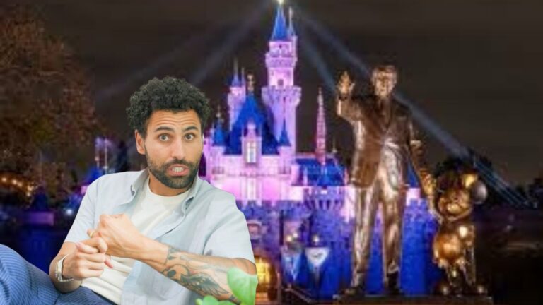 Man with tattoos in a light shirt sits in the foreground as a colorful, lit castle appears in the background at night.