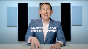 Host in a blue plaid suit smiles at the camera with a desk in front; overlay reads 'Mastering Real Estate Rapport'.