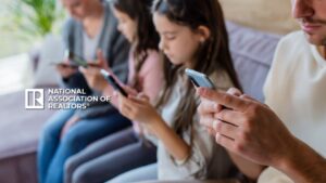 Group of people sitting on a couch using smartphones, with the National Association of Realtors logo in the foreground.