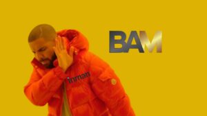 Man in an orange puffer jacket raises a hand in a stop gesture against a mustard-yellow background; large gray-to-gold 'BAM' text on the right, with 'inman' printed on the chest area.