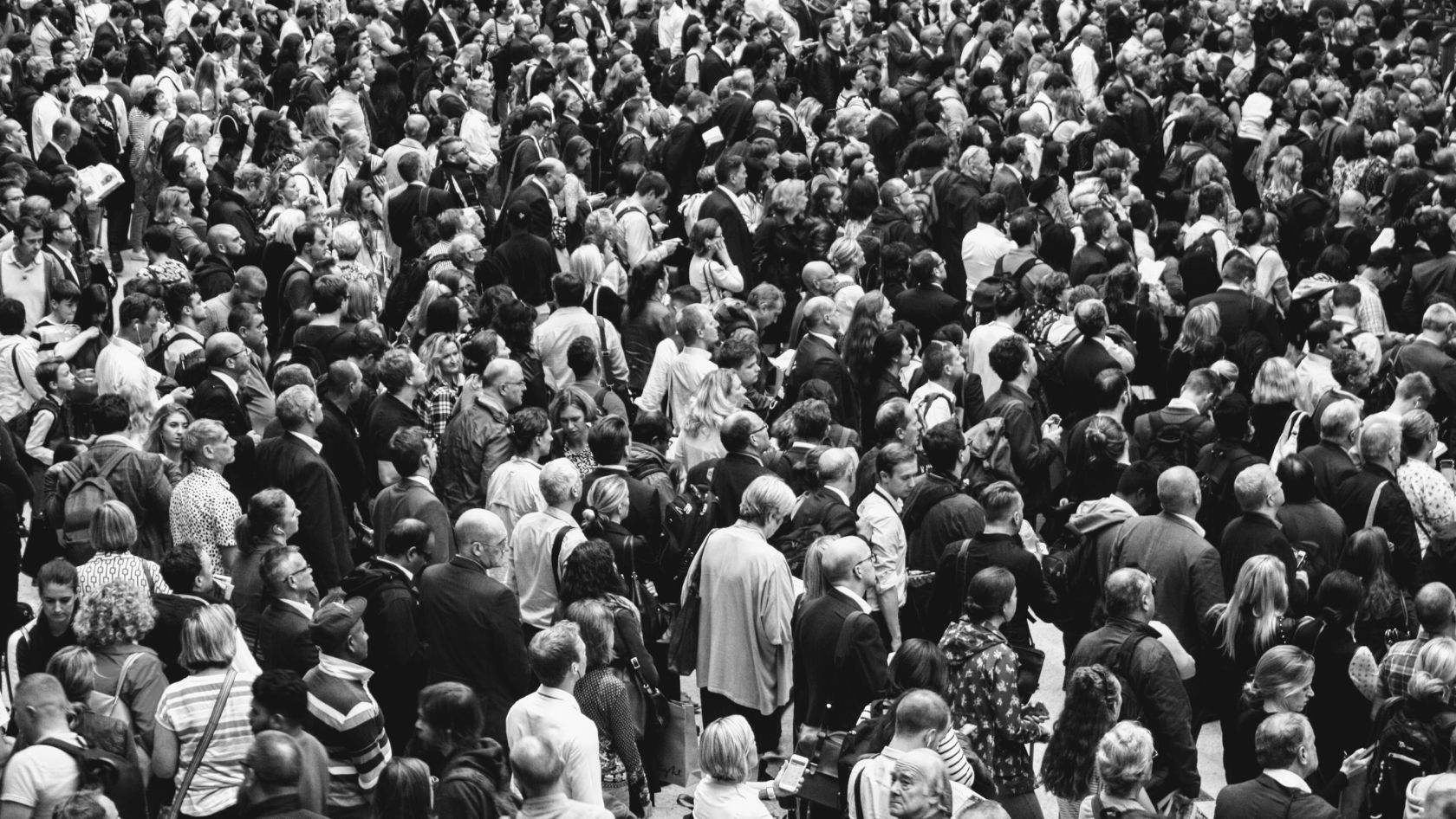 Dense crowd of people standing closely together in a public space (black and white photo).