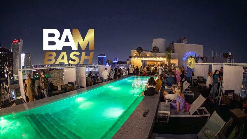 Crowd of people socializing around a glowing rooftop pool at night, with a bold BAM BASH graphic overhead.
