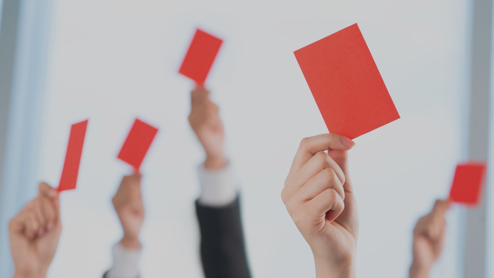 Hands raise red cards in the air, signaling disapproval or protest.
