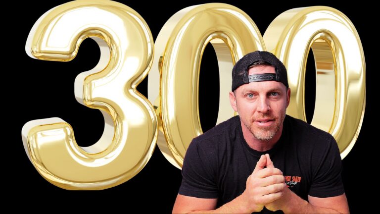 Man in a black shirt and backward cap sits in front of oversized shiny gold 3000 digits on a black background, hands clasped together in front.