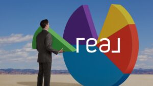 Man in a suit examines a giant colorful pie-chart sculpture in a desert, with the word 'real' overlaying the chart, suggesting data/analytics concept.