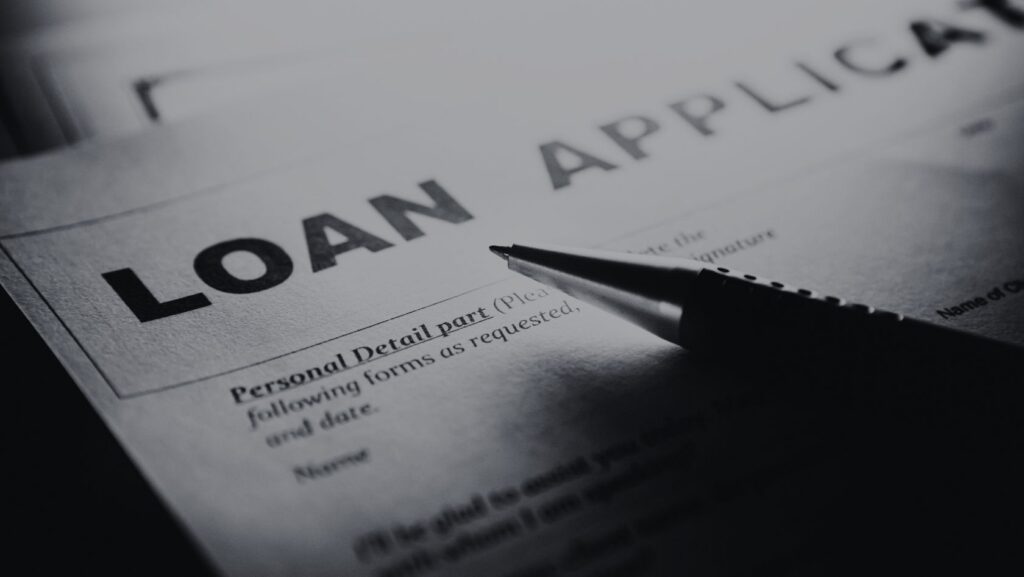 Close-up of a loan application form with the bold title 'LOAN APPLICATION' and a pen resting on it, ready to fill in details.