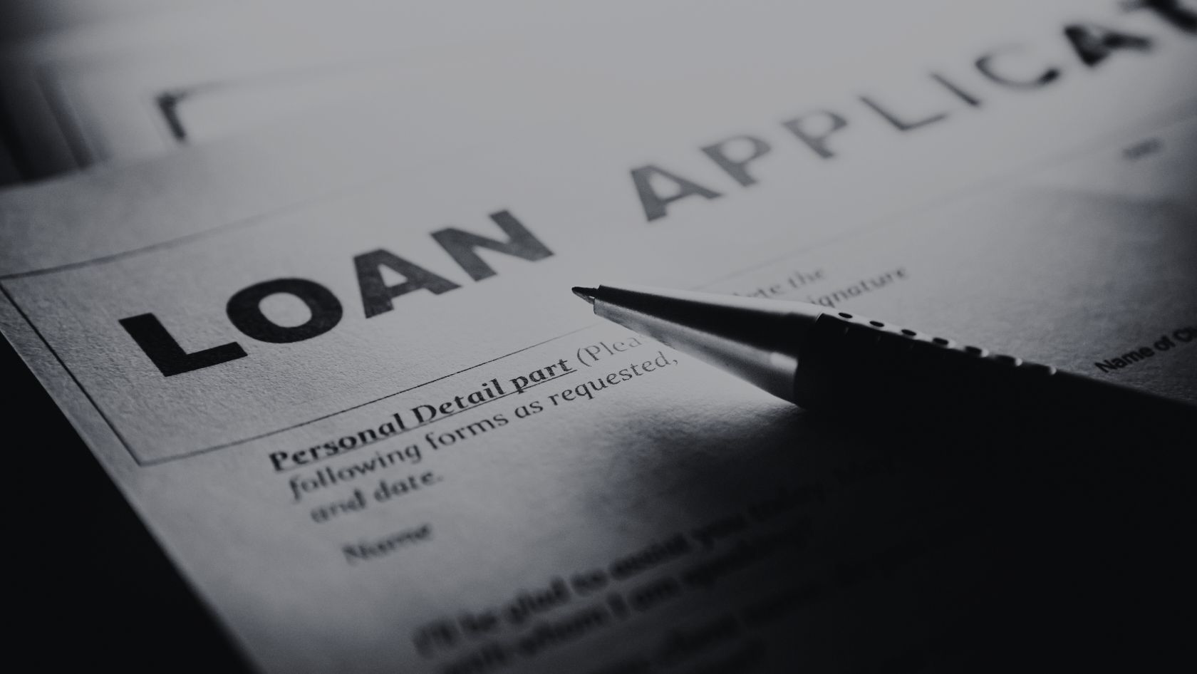 Close-up of a loan application form with the bold title 'LOAN APPLICATION' and a pen resting on it, ready to fill in details.