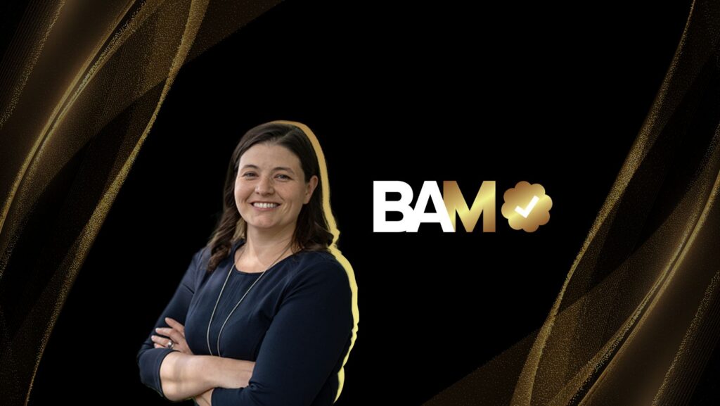 Smiling woman with arms crossed beside the BAM logo on a black and gold abstract background.