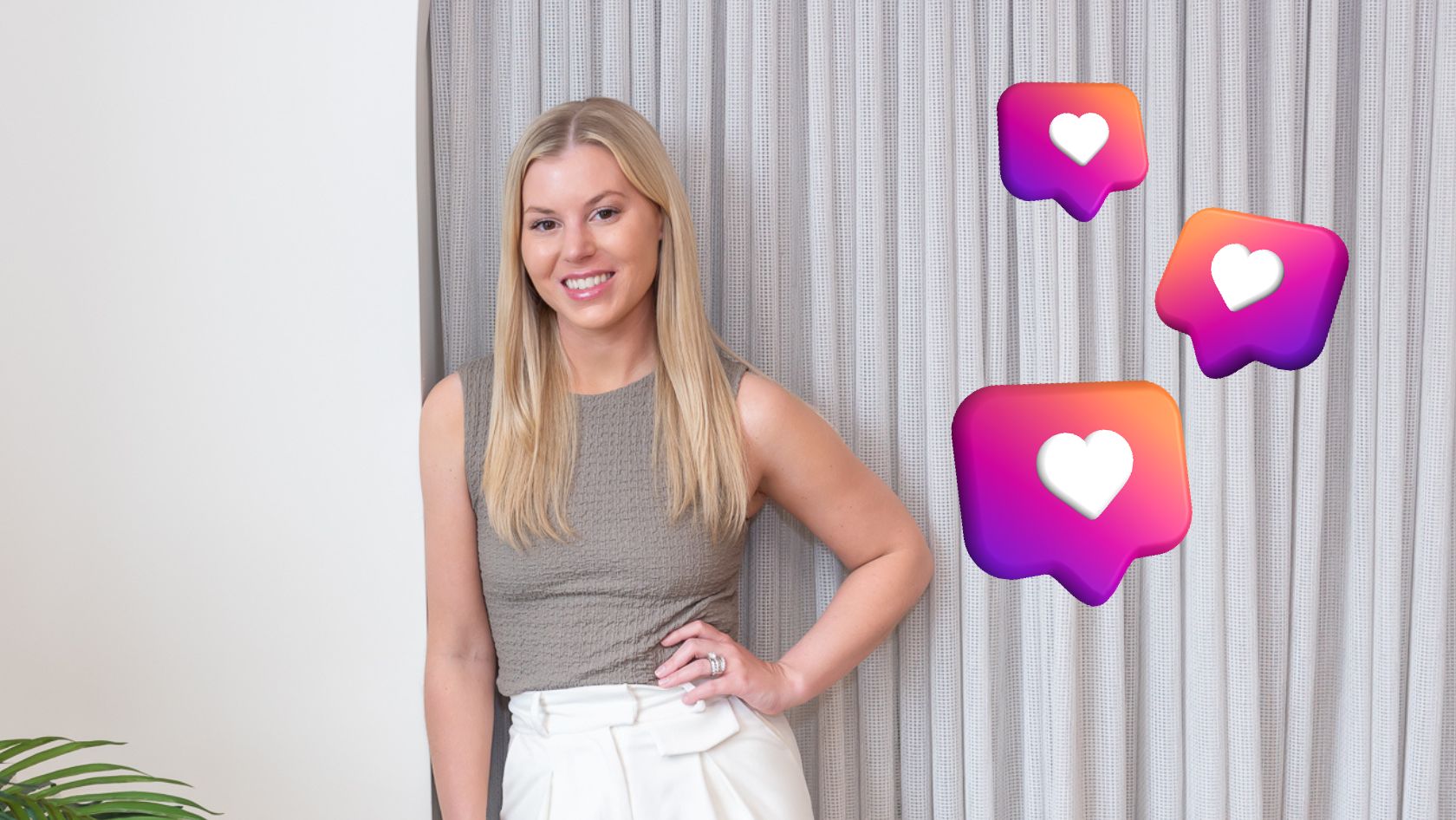 Portrait of a smiling blonde woman in a gray sleeveless top and white pants, standing by a curtain, with three floating like icons nearby to convey social media engagement.