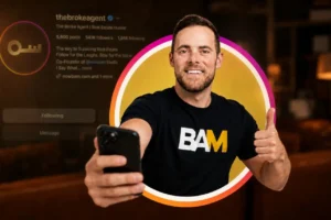 Man taking a selfie with a smartphone, smiling, wearing a black BAM T‑shirt, inside a colorful circular frame behind him.