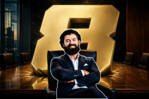 8 Closes From Alex Hormozi That Work for Real Estate Agents (1) - BAM Bearded businessman in a navy suit sits with arms crossed in a boardroom, a large gold Bitcoin behind him.