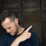 Stop Turning Your Content Into a Business Card (1) - BAM - BAM Man in a navy shirt looks down and points to the right, drawing attention off-screen against a dark background.