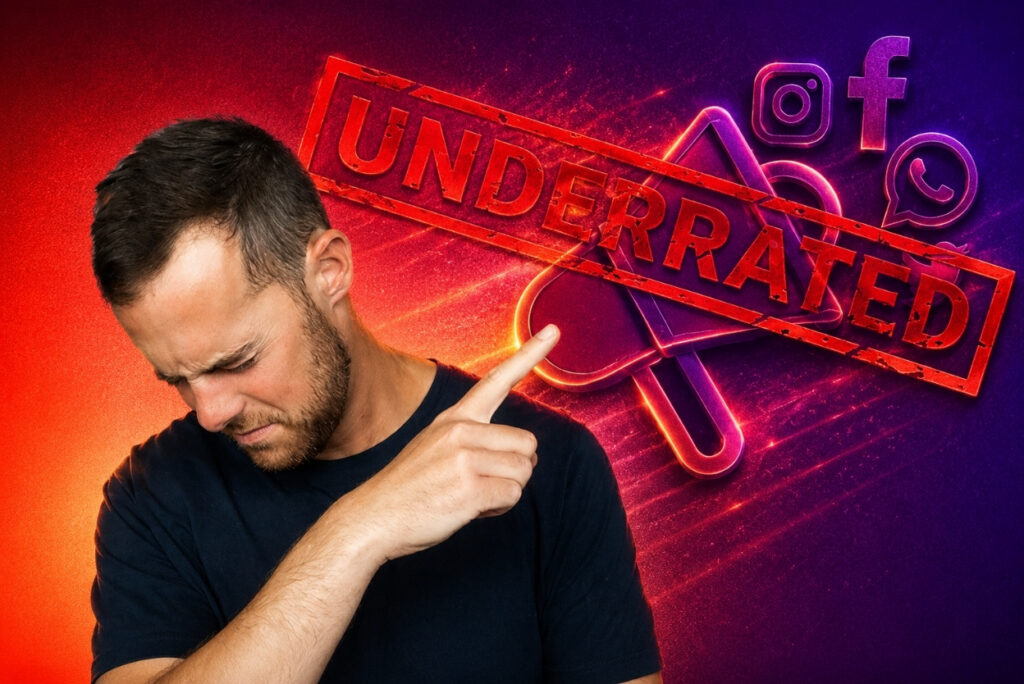 Man with short hair and beard looks down while pointing at a red 'UNDERRATED' stamp across neon social media icons.