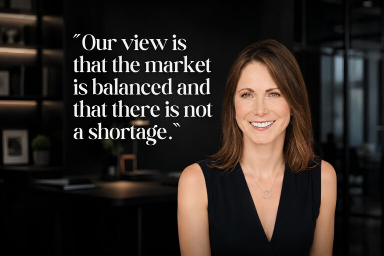 Is There a Housing Shortage in the U.S. Right Now Ivy Zelman Says No - BAM - BAM Smiling woman in a black sleeveless top stands in a modern office beside a large white quote about market balance on a dark wall .